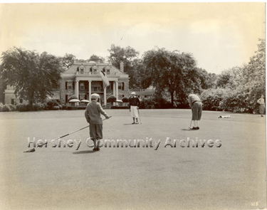 Golfers putting at the new Hershey Country Club golf course’s 18th hole. Milton Hershey’s home, High Point, served as the clubhouse. 1933