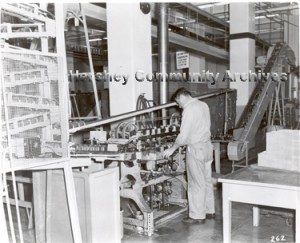 In 1956 Hershey Chocolate Corporation began manufacturing its own tins for Hershey’s syrup. Here an employee monitors the progress of a can labeler. ca.1960-1970