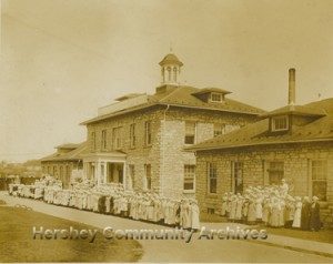 The wrapping department poses in front of Hershey Chocolate factory offices. 1915