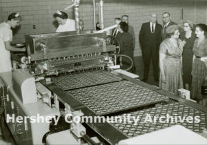 Guests watch employees work on the moulding line of the new Reese factory, November 30, 1957