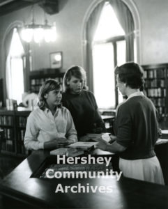 Until it moved to its new location, the public library was a important part of the Community Building's services. Librarian Irene Heaps checks books out for two young patrons, ca. 1965-1975