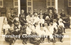 Milton Hershey with Hershey Industrial School students, seated on the steps of The Homestead, 1923
